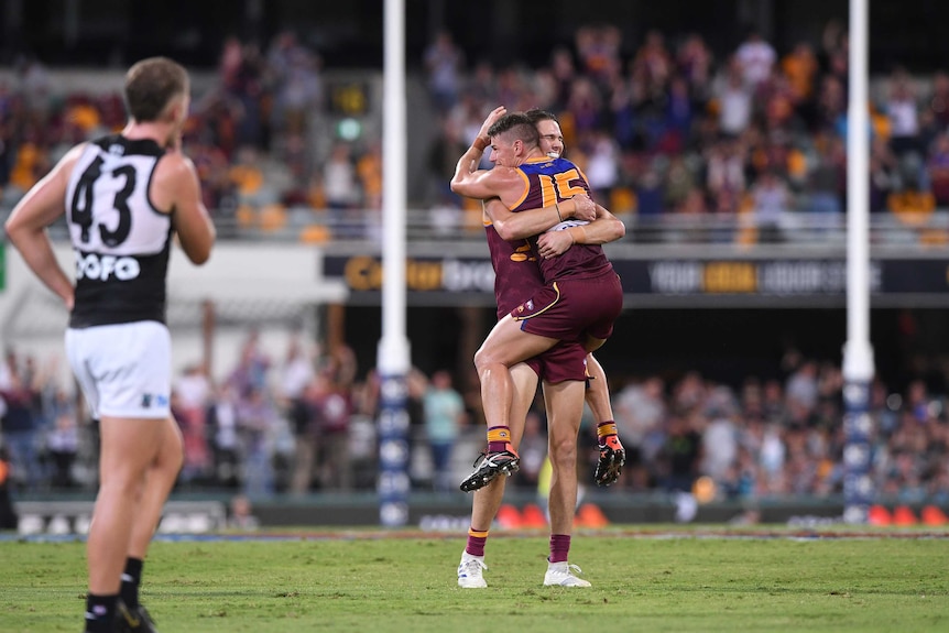 An AFL player jumps into his teammates' arms after they win their game.