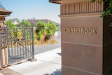 The word Cranbrook in gold on a sandstone column at the gates of a school.