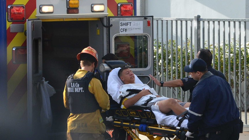 Medical personnel load an injured person on a stretcher into an ambulance.