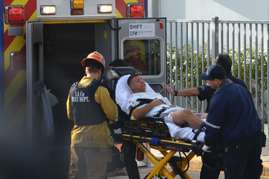 Medical personnel load an injured person on a stretcher into an ambulance.