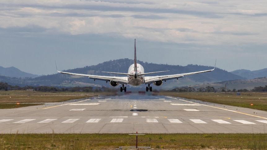 The rear of a plane with wheels down about to land on a runway 