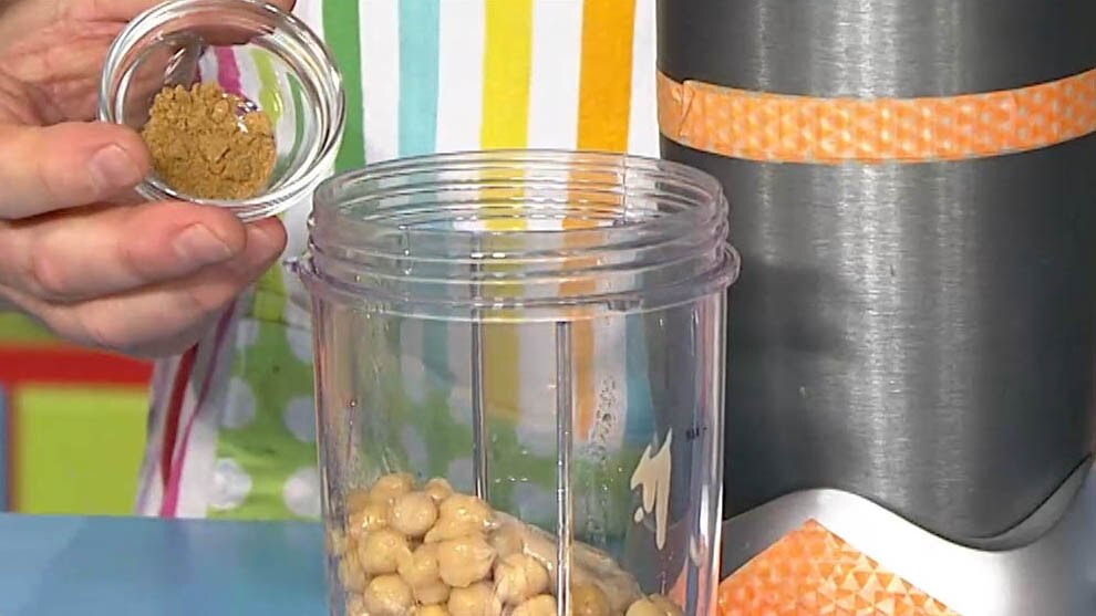 Chickpeas in a blender and some cumin in a bowl