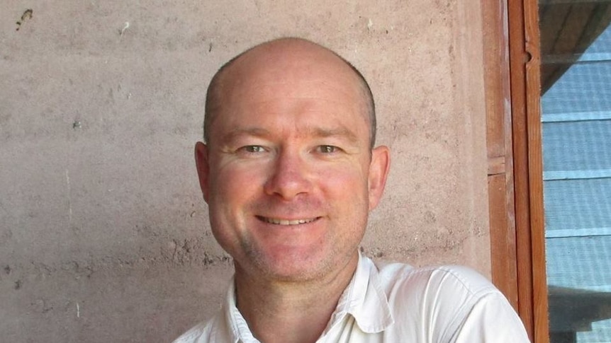 A headshot of a bald man in a white shirt.