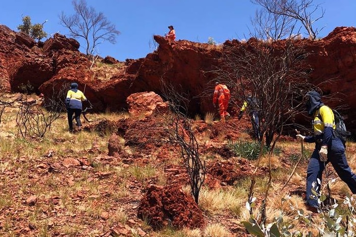 emergency workers searching among red rock crevices in the Pilbara.