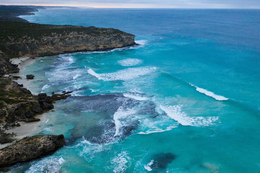 A beach and rocky coastal cliffs seen from the air