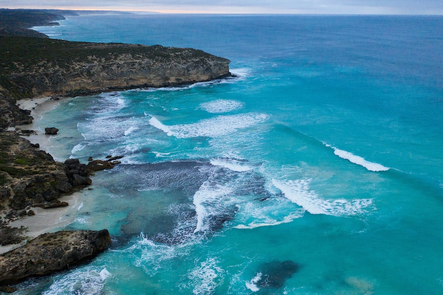 A beach and rocky coastal cliffs seen from the air