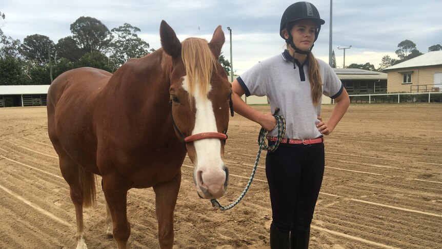 Student Serena Stanley standing by a horse.