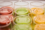 Three rows of colourful juices and smoothies in glass cups.