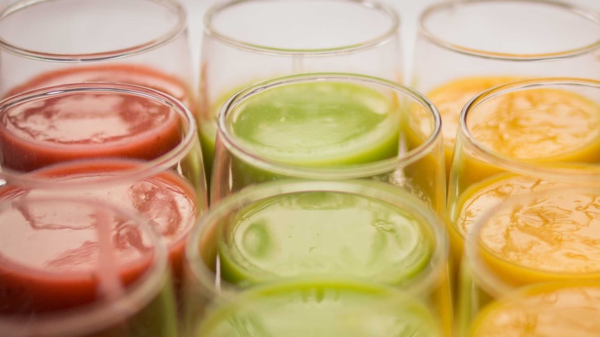 Three rows of colourful juices and smoothies in glass cups.