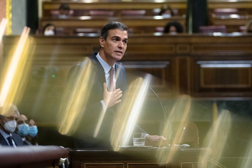 A man stands behind a lectern in a parliament.