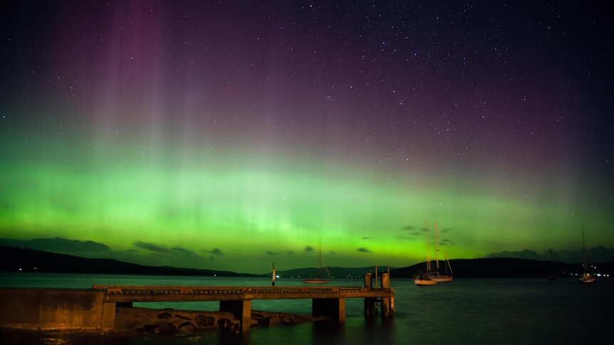 The Aurora Australis (Southern Lights) covers the sky.