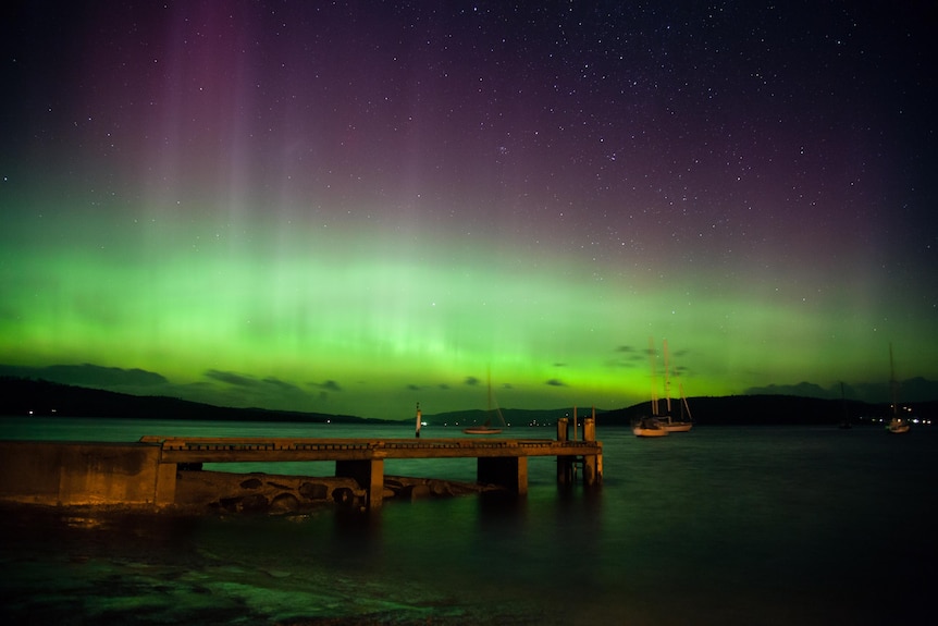 The Aurora Australis (Southern Lights) covers the sky.