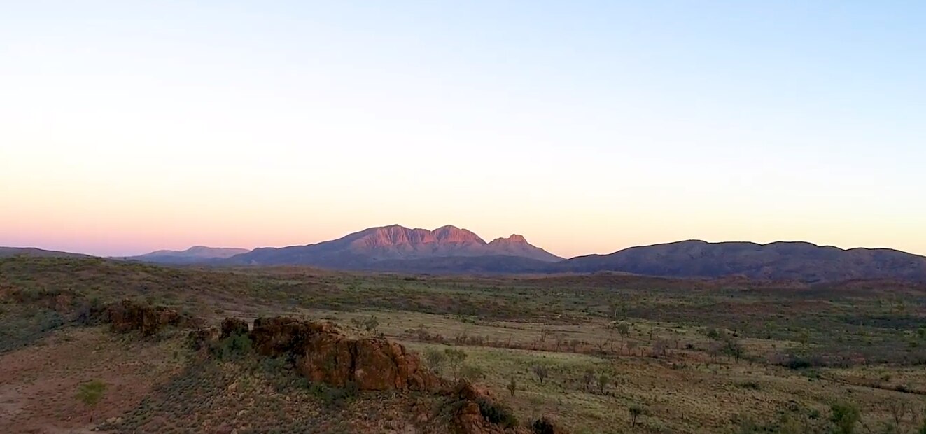 Sunrise with a large outcrop of rock in background