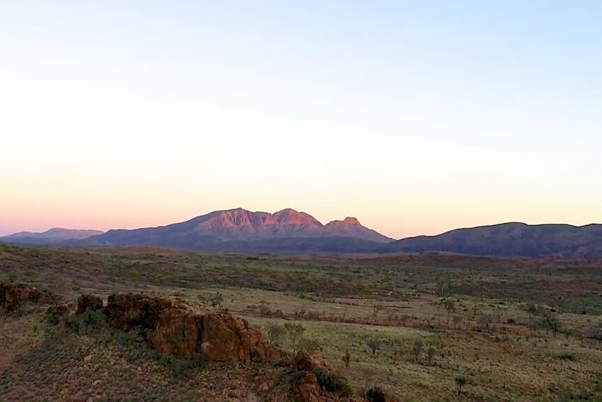 Sunrise with a large outcrop of rock in background