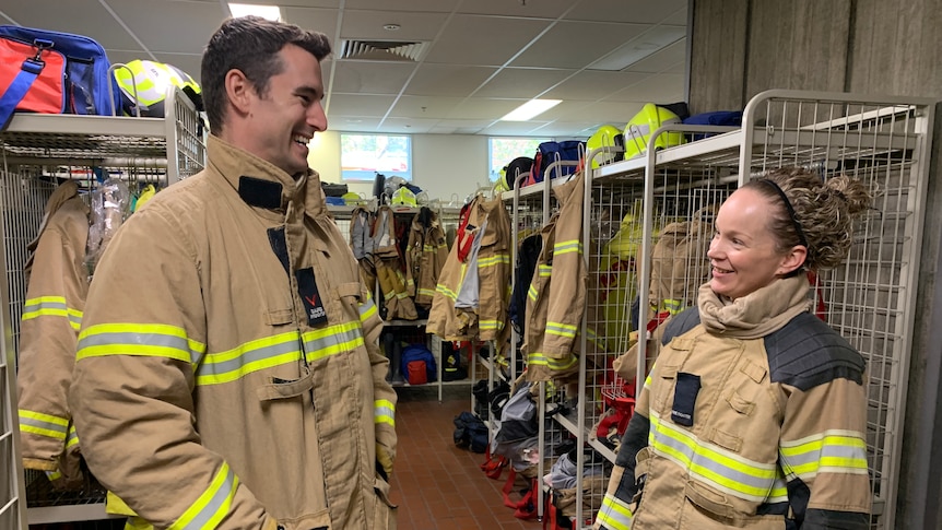 A man and woman in a locker room in firefighting apparel