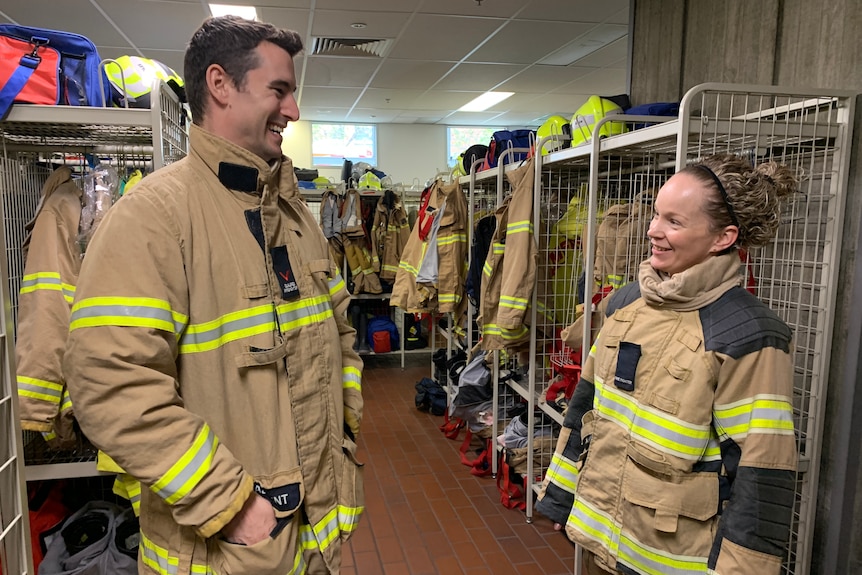 A man and woman in a locker room in firefighting apparel