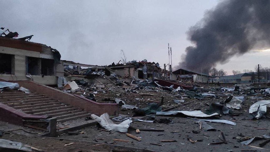 Destroyed remnants of buildings with black smoke coming from the rubble.