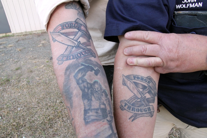 Two arms with a Forge Through logo tattooed on them.