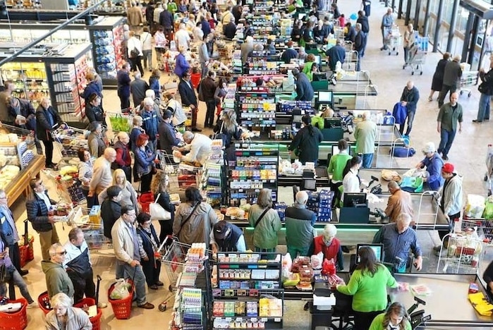A crowd of people shopping in a supermarket.