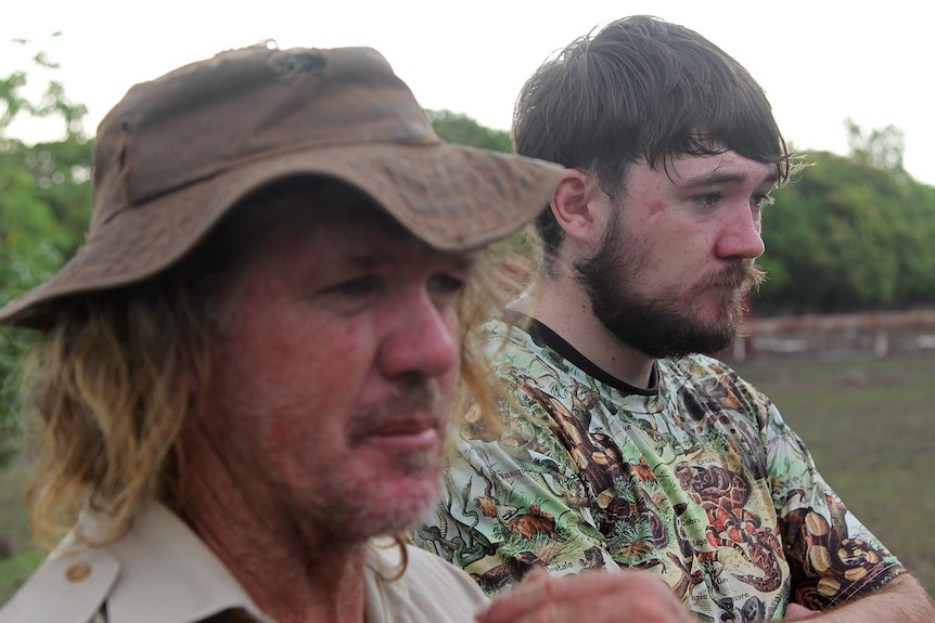 A photo of Phillip and Trevor Sullivan looking on at a pet crocodile.