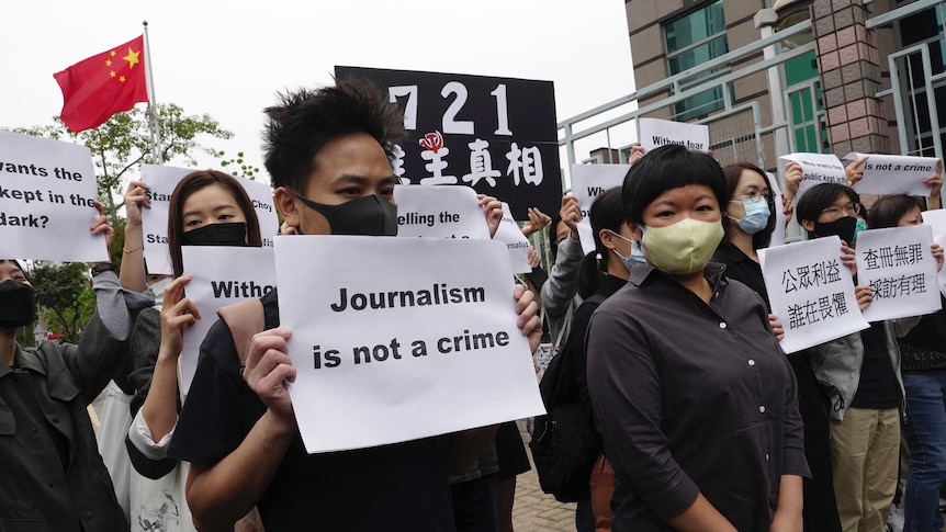 Protesters stand outside a courthouse in Hong Kong with placards reading 'journalism is not a crime'.