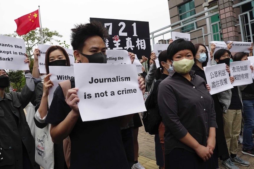 Protesters stand outside a courthouse in Hong Kong with placards reading 'journalism is not a crime'.
