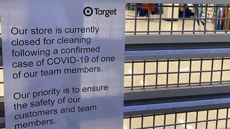 A paper sign on a Target store's shutters that says the store is closed for cleaning after a team member contracted COVID-19.