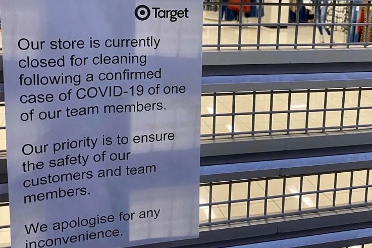 A paper sign on a Target store's shutters that says the store is closed for cleaning after a team member contracted COVID-19.