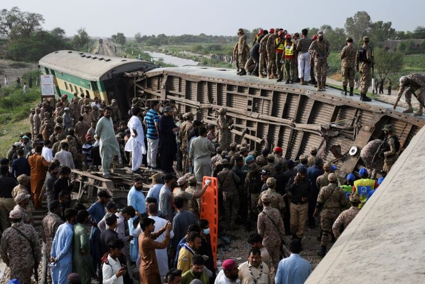  Pakistani army soldiers and rescue workers gather to search for survivors at the wreck of a derailed train