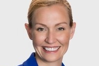 A headshot of a blonde woman smiling and wearing a royal blue jacket.