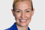 A headshot of a blonde woman smiling and wearing a royal blue jacket.