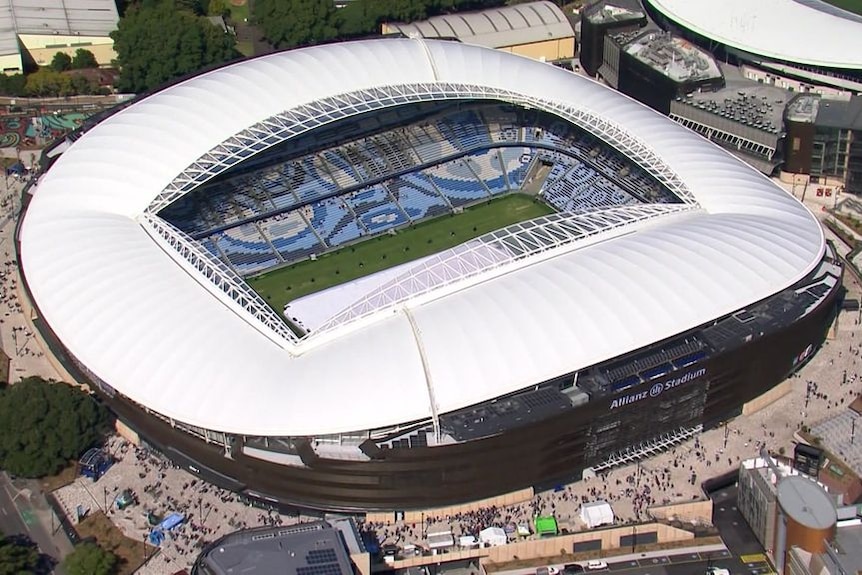 An aerial view of a football stadium, with a roof over the banks of seats but the pitch open to the sky.