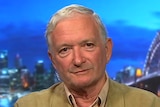 Nick Greiner sits in an ABC studio against the backdrop of the Sydney Harbour Bridge.