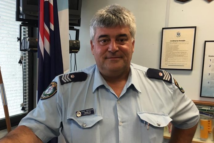 Sergeant Paul Batista stands in front of the Australian flag at the police station in Queanbeyan.