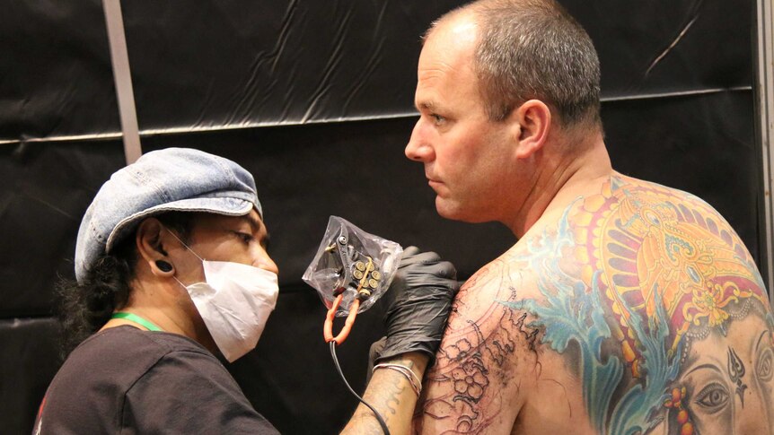 A tattooist works at the Australian Tattoo and Body Art Expo 2014, Perth