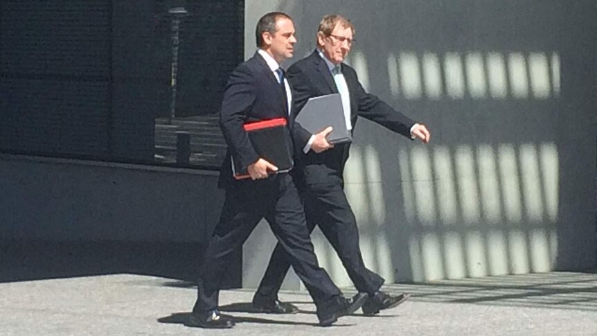 LNP Member for Moggill Bruce Flegg (right) and his lawyer enter the Brisbane court complex.