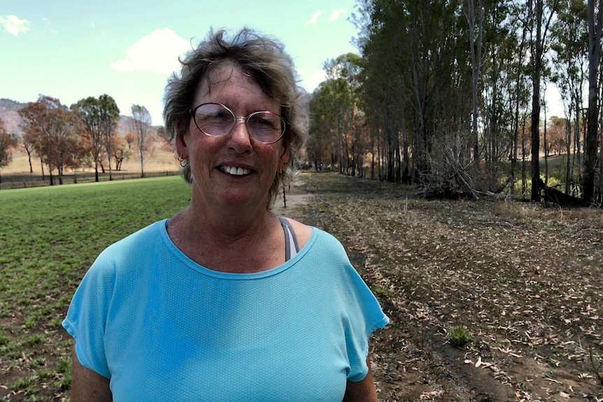 Kayleen Moss smiles at the camera with a burnt paddock behind her.
