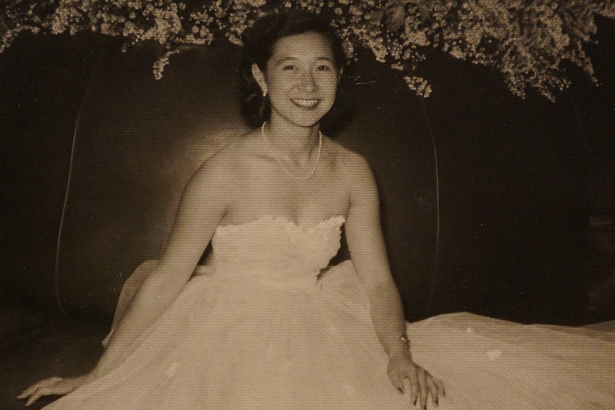 Fay Chong sits smiling in a long white dress 