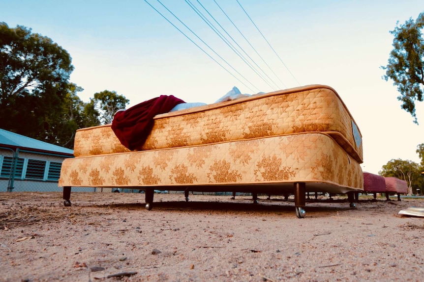 A yellow mattress outside in the dirt