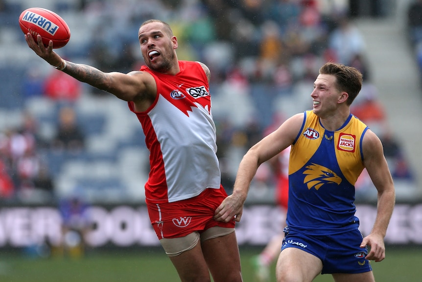 A Sydney Swans AFL player attempts to mark the ball with his right hand against West Coast.