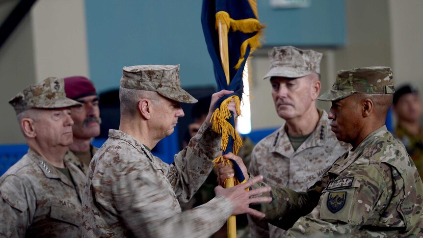 Former NATO commander US General John Allen hands over a flag to US General Joseph Dunford.