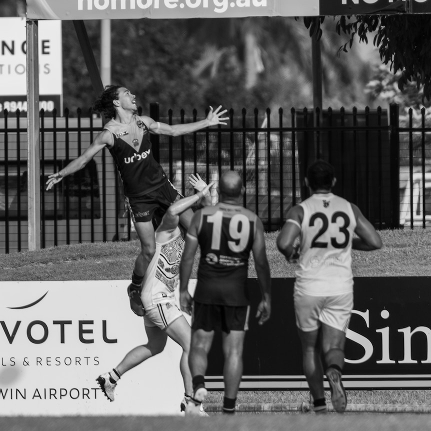 Malcolm Rosas Jnr flies high above a pack for a mark. Photo taken in black and white.