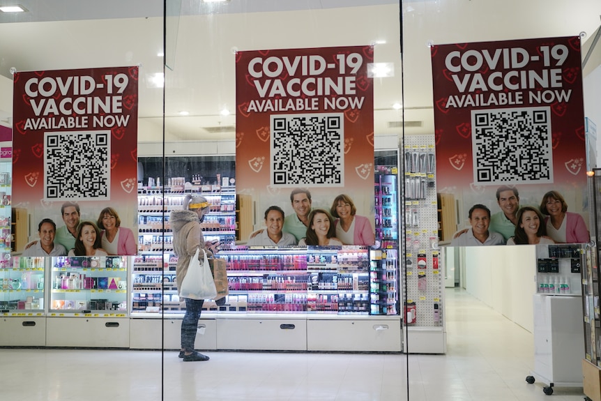 The front window of a pharmacy with 'vaccine avialable here' signs