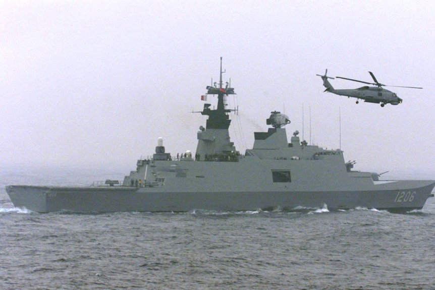在这张 2003 年的档案照片中，一架台湾反潜直升机飞越了一艘法国拉斐特级护卫舰。