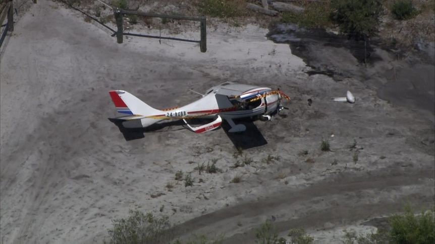 A damaged ultra light plane lying on dirt.