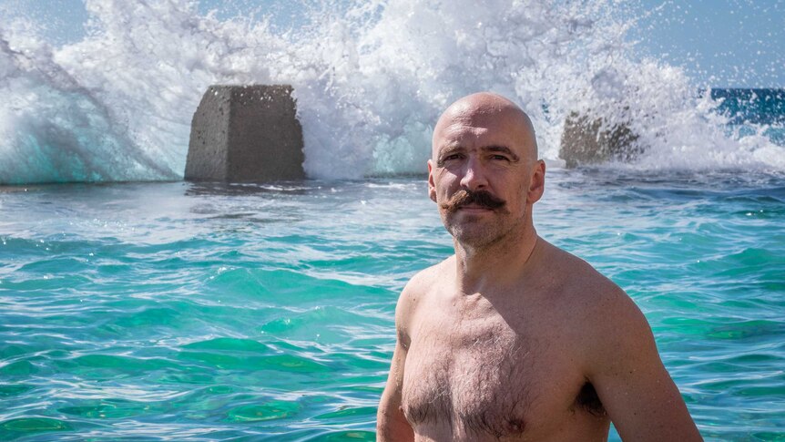 Man sporting a large moustache, stands with his hands on his hips, ready to get wet at the Coogee ocean pool.
