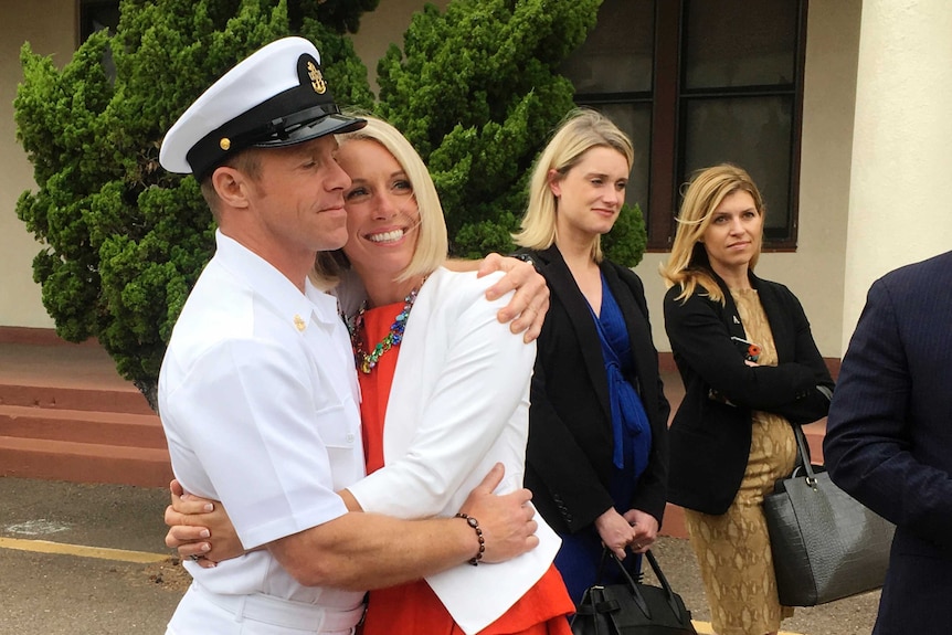Edward Gallagher in Naval uniform (left) hugs his wife after leaving a courtroom.