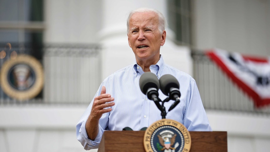 us president joe biden stands behind microphone front on wearing button up shirt