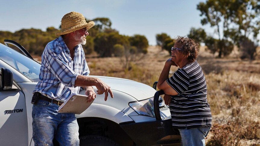 Neil Seymour and Aunty Hazel talk while leaning on a vehicle.