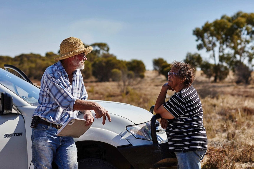 Neil Seymour and Aunty Hazel talk while leaning on a vehicle.